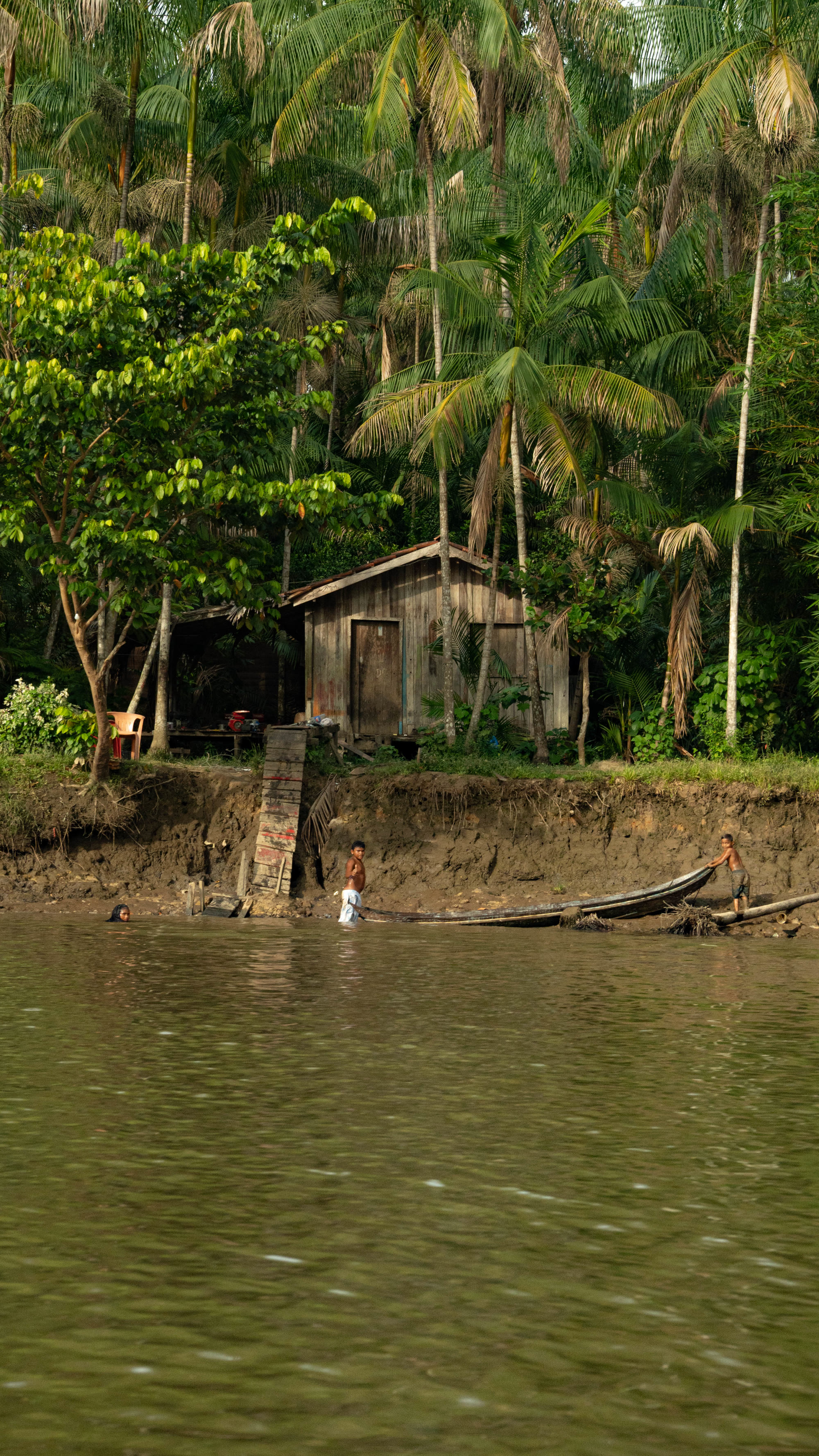 Crianças ribeirinhas puxando canoa na luz dourada