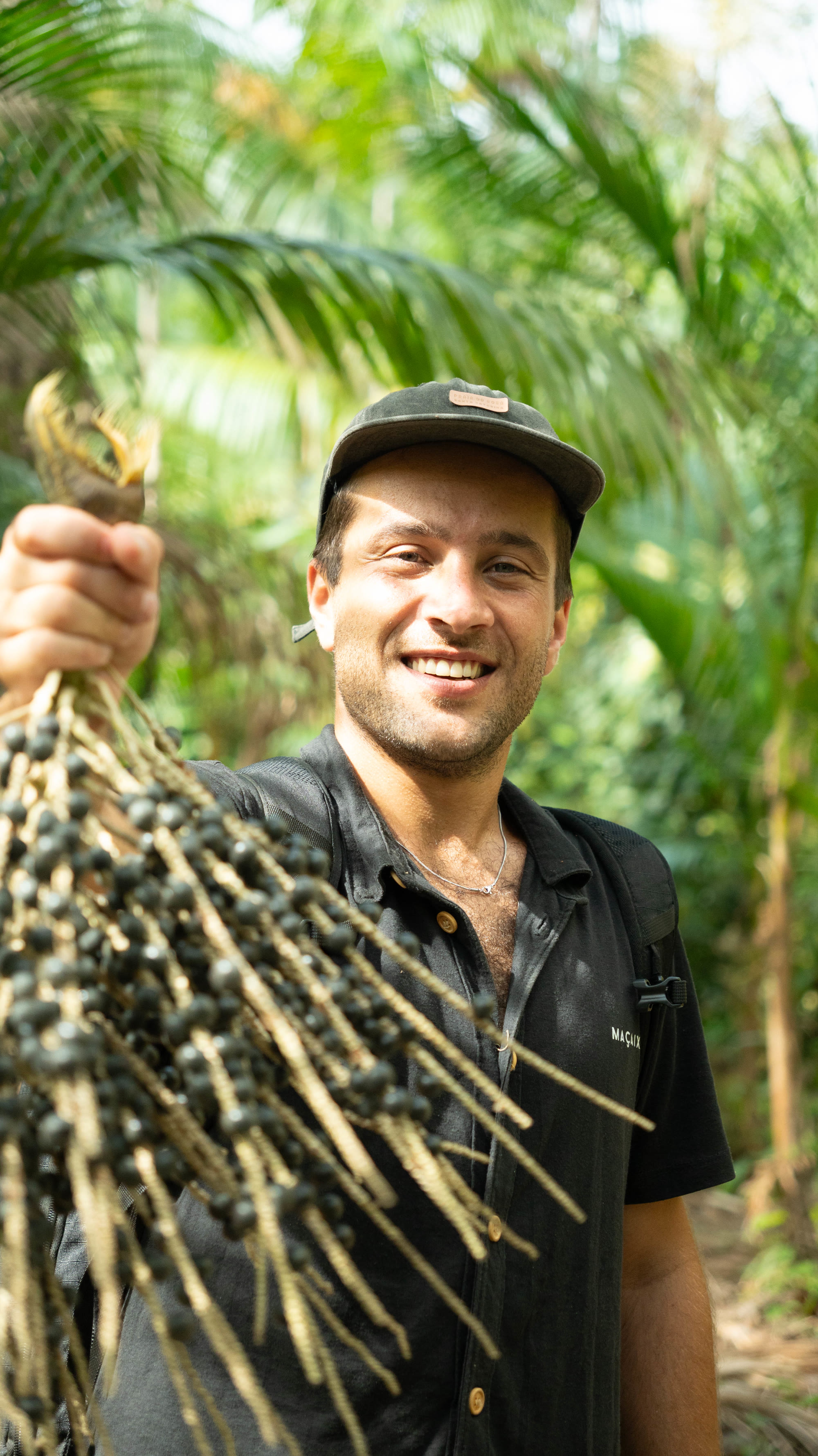 Fundador da Maçaix segurando um cacho de açaí na floresta